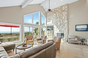 A spacious living room with a large window, a stone wall, and a ceiling fan.