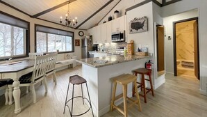A kitchen with a large island, white cabinetry, and a view of the outdoors. - Summer is here, cool down on Beech mountain! (Beech Mountain)