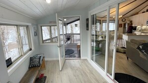 A cozy interior with a wooden floor, a sliding glass door leading to a balcony, and a kitchen area with cabinets and appliances. - Summer is here, cool down on Beech mountain! (Beech Mountain)
