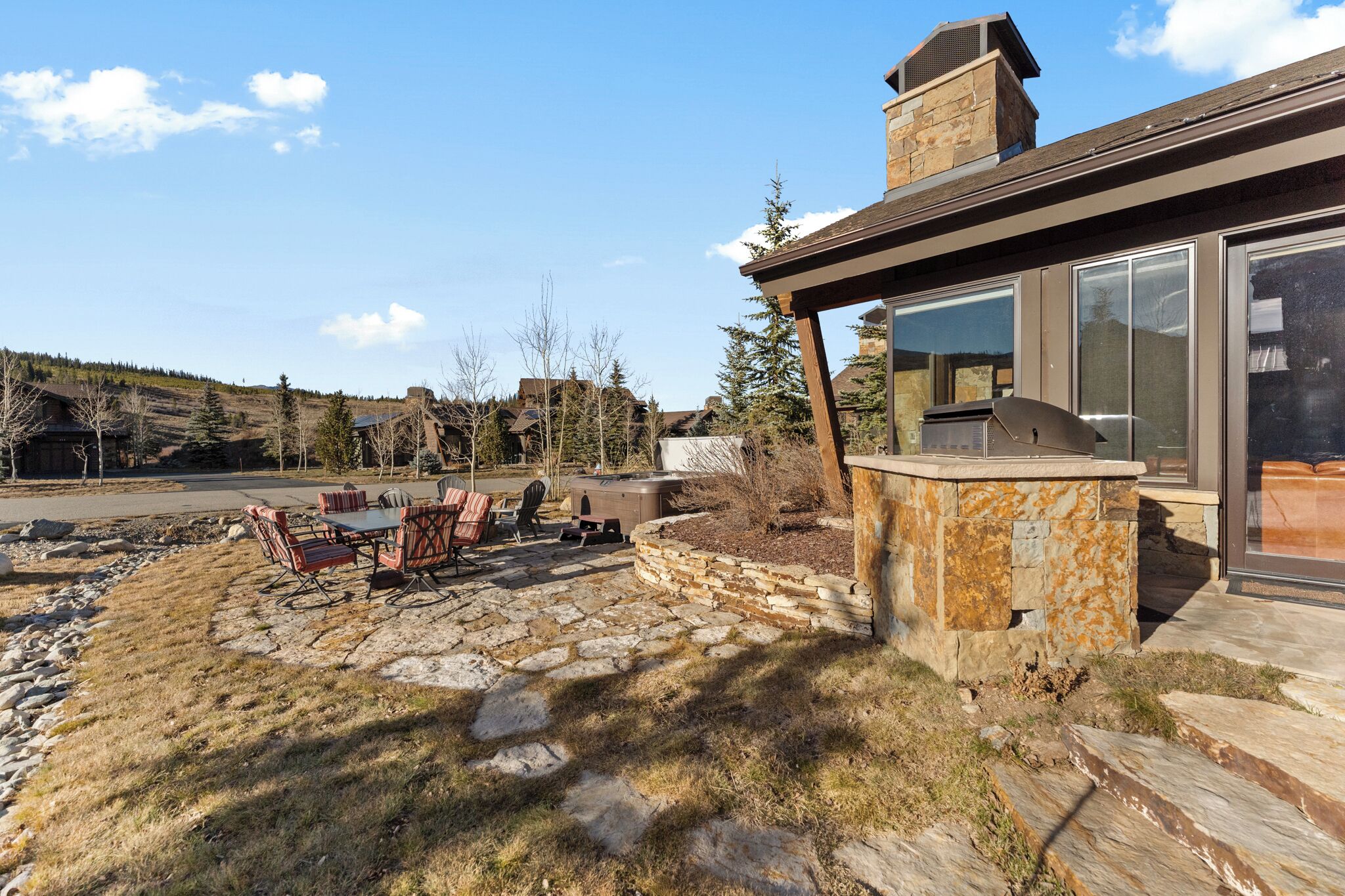 A patio with stone flooring, outdoor furniture, and a stone fireplace.