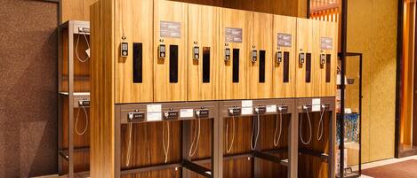 A row of wooden lockers with numbered keys, a security camera, and a glass door.