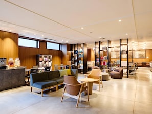 A modern lounge area with seating, a coffee station, and bookshelves. - Comfort Hotel ERA Kyoto Horikawagojo (Kyoto)