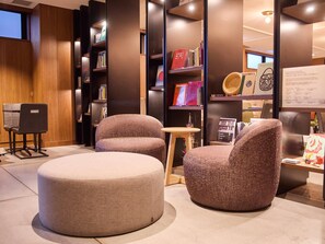 Ein modernes Interieur mit zwei Polsterstühlen, einem runden Hocker und einem kleinen Tisch.