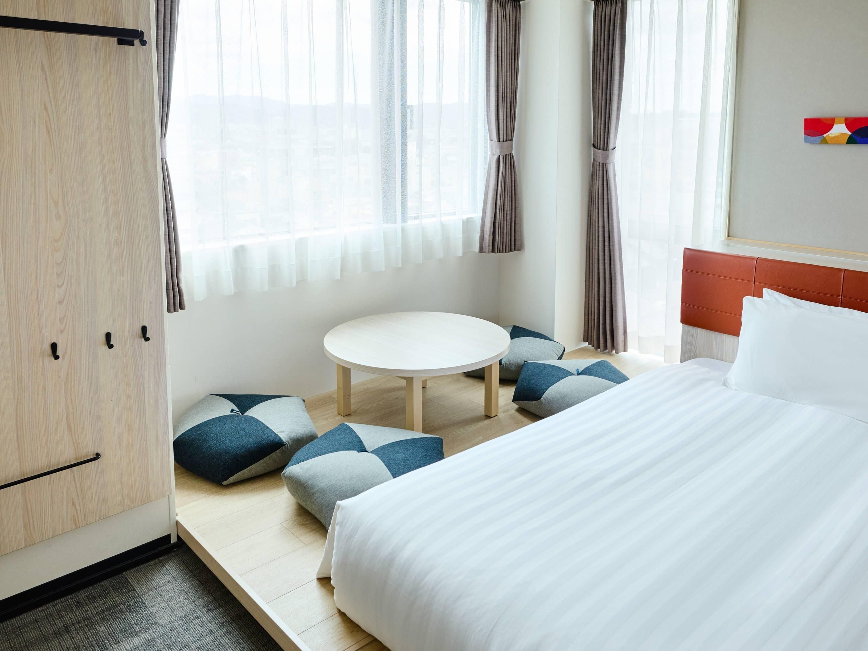 A hotel room with a bed, a round table, and a wardrobe.