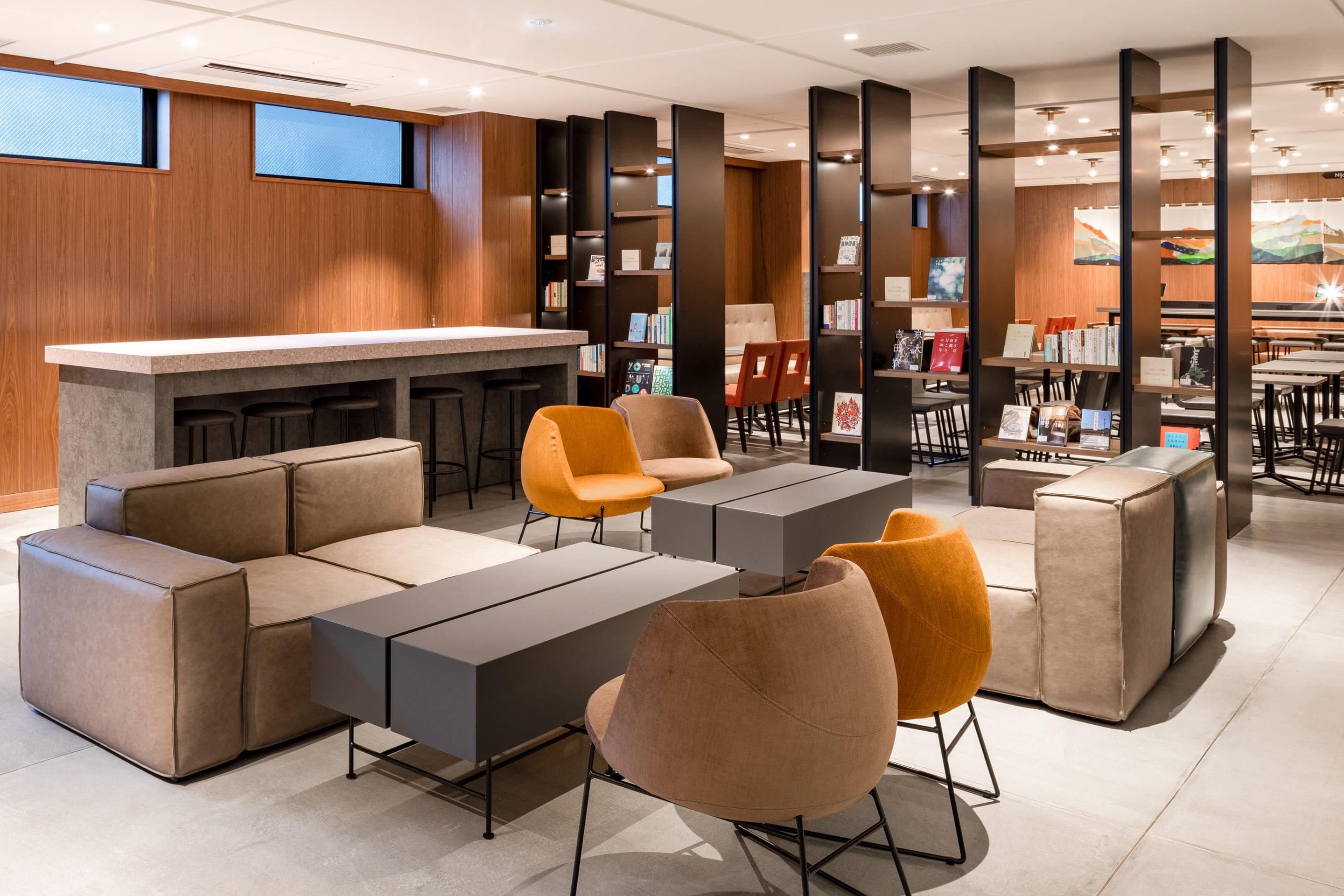 Un área lounge moderna con bar, asientos y una estantería.