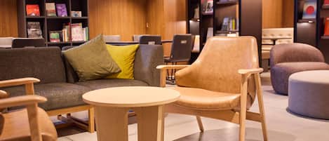 Une bibliothèque moderne avec un canapé, des fauteuils et une table ronde.