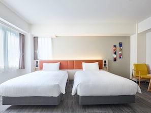 Habitación de hotel con dos camas, cabecera, una silla y una pared con un cuadro.