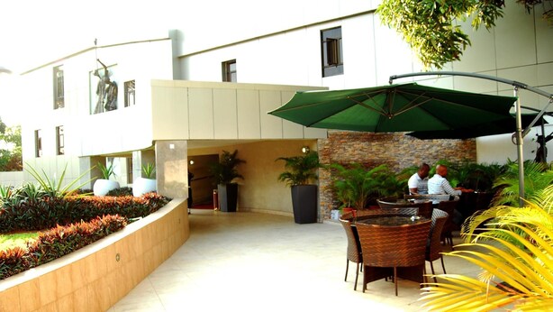 An outdoor patio area with a seating arrangement, potted plants, and a stone wall. - Best Western Starfire Hotel (Lagos)