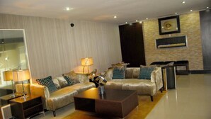 A modern living room with a sectional sofa, a coffee table, and a TV mounted on the wall. - Best Western Starfire Hotel (Lagos)