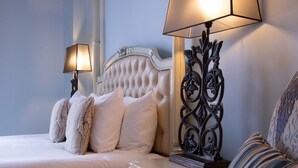 A hotel room with a tufted headboard, two bedside lamps, a decorative metal stand, and a striped armchair. - Villa Palma Boutique Hotel (Panama City)