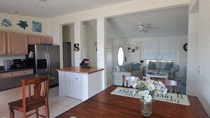 A kitchen with wooden cabinets, a refrigerator, and a dining area with a wooden table and chairs.
