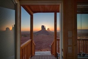 Ein hölzerner Balkon mit Blick auf eine Wüstenlandschaft und einer markanten Felsformation.