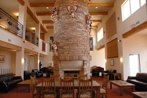 Un vestíbulo amplio con chimenea de piedra, muebles de madera y un balcón con barandillas.