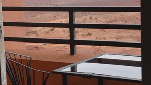 A balcony with a table and chairs, overlooking a desert landscape with a prominent rock formation. - The View Hotel (Oljato-Monument Valley)