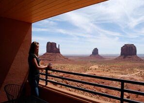 Eine Person auf einem Balkon mit Blick auf eine Wüstenlandschaft und Felsformationen.