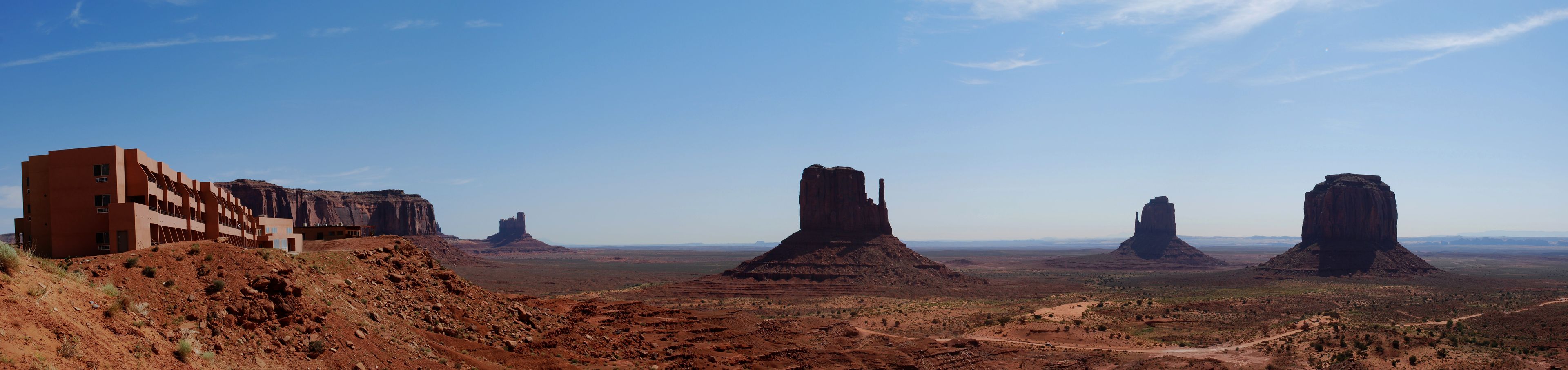 A desert landscape with rock formations and a building on a hill.