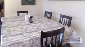 A dining area with a large table, four chairs, a painting of a forest, and three flower pots on a shelf above the table. - 30 miles from Breck!! Avoid I70 traffic. (Fairplay)