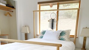 Ein Bett mit Holzrahmen, weißer Bettwäsche und einem gemusterten Teppich.