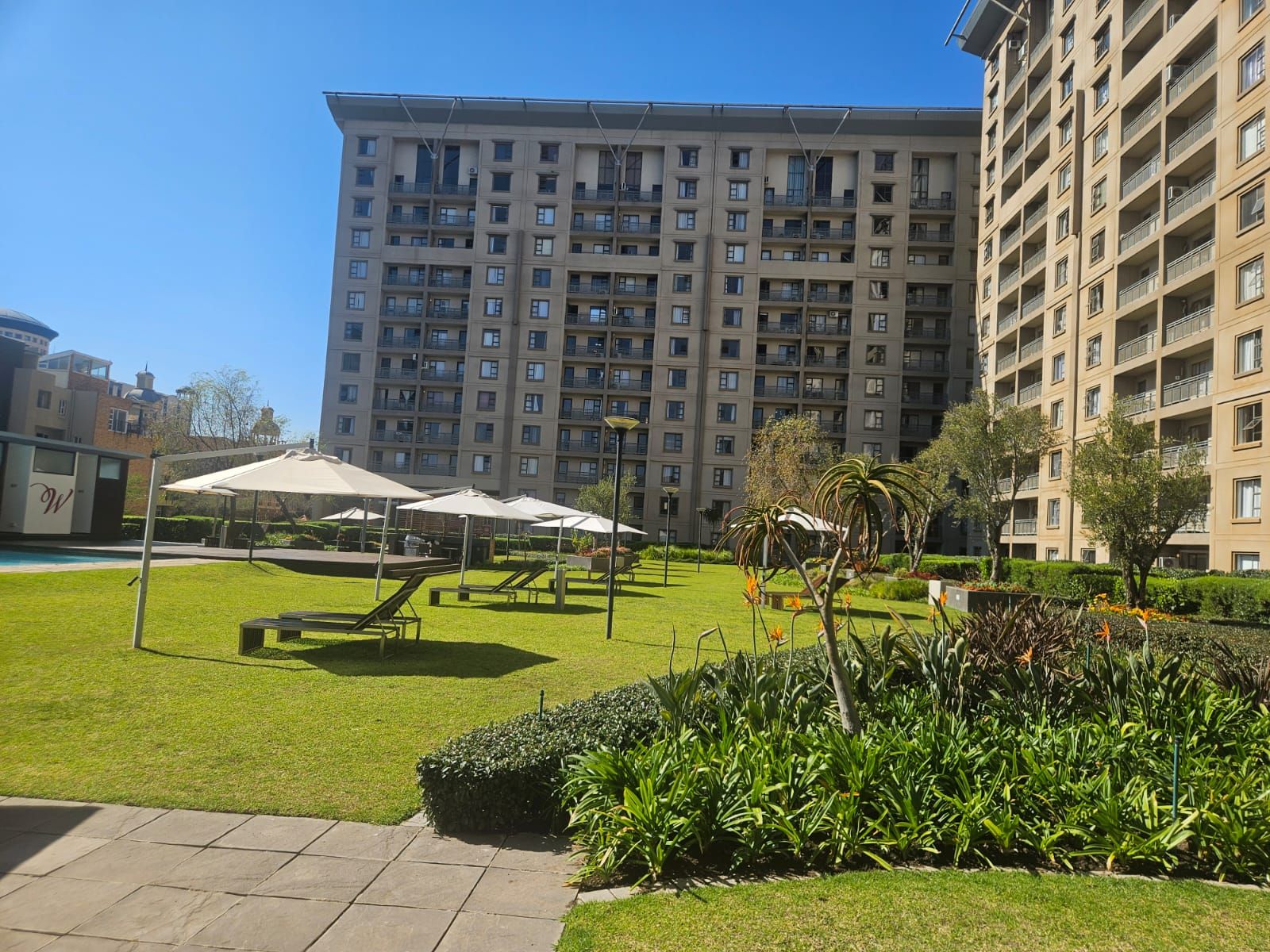 Un edificio residenziale con numerosi balconi, un prato curato e zone relax all'aperto.