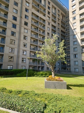 A multi-story residential building with balconies and a well-maintained lawn with a tree. - Sandton Westpoint Luxury Apartments (Sandton)