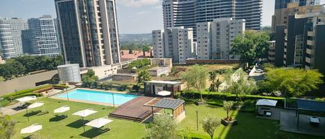 Un quartier résidentiel doté d’une piscine, de chaises longues et d’un petit pavillon.