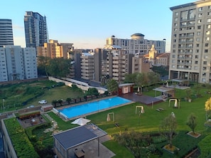 Ett bostadsområde med en swimmingpool, grönområden och moderna byggnader.