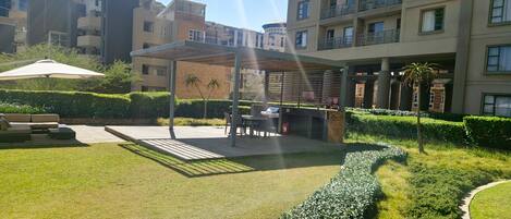 A courtyard with a covered seating area, a pathway, and well-maintained hedges.