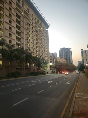 A multi-story building with balconies, a clear sky, and a road with vehicles. - Sandton Westpoint Luxury Apartments (Sandton)