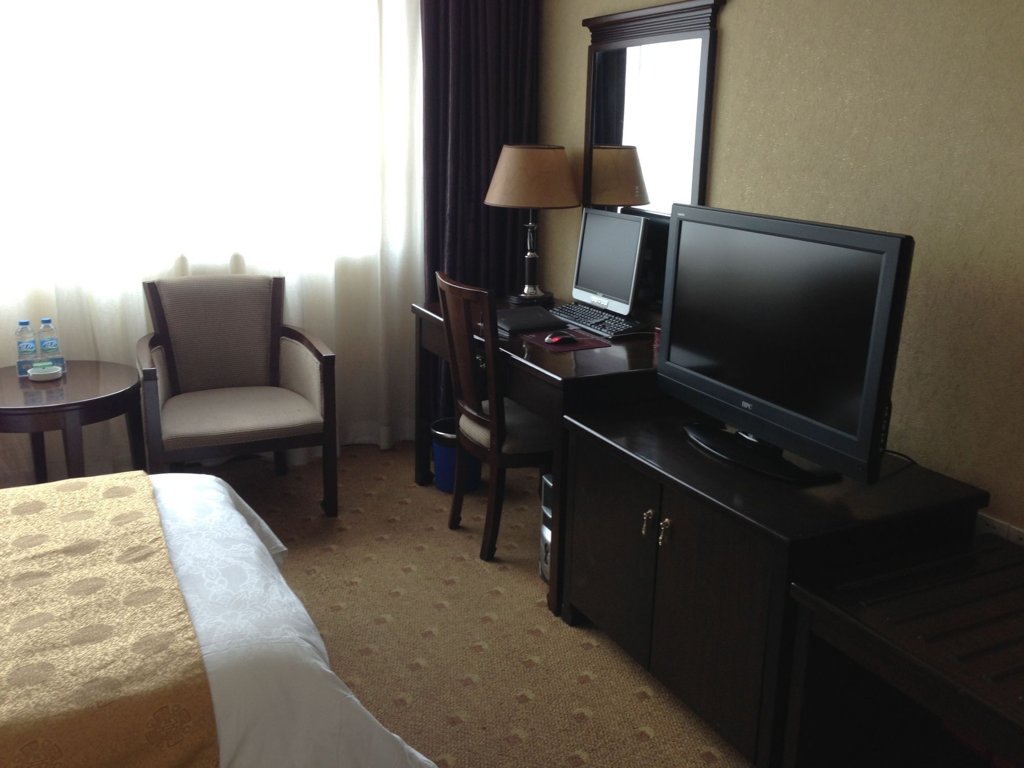 Une chambre d’hôtel comprenant un lit, un bureau avec un ordinateur, une chaise, une lampe et un téléviseur.