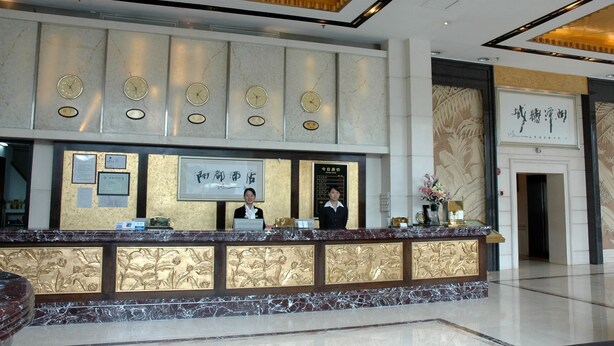 A hotel reception area with a marble counter, multiple clocks, and a framed sign above the counter. - Run Du Hotel (Guangzhou)