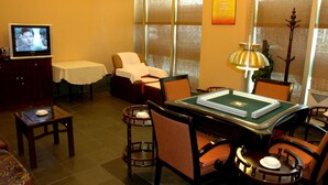 A hotel room with a desk, chairs, a TV, a sofa, and a window with blinds. - Run Du Hotel (Guangzhou)