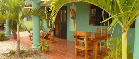 A house with a patio, wooden furniture, and potted plants.