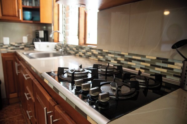 A kitchen with a gas stove, wooden cabinets, and a tiled backsplash.