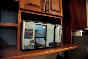 A microwave oven with a digital display, placed on a wooden countertop in a kitchen.
