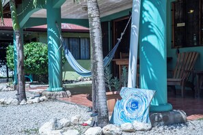 A covered outdoor area with a hammock, a sign reading "Casa de Cielo", and a patio with chairs and a table.