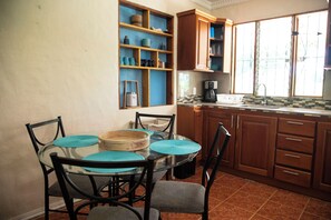 A kitchen with wooden cabinets, a coffee maker, and a window with blinds.
