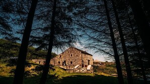 A stone building with a sloped roof, surrounded by trees and grass. - Laythams Holiday Lets Retreat (Clitheroe)