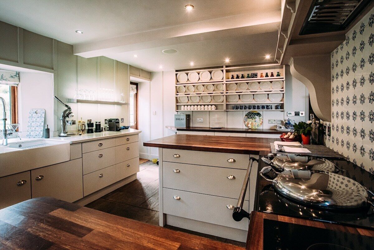 A modern kitchen with white cabinetry, a wooden countertop, and a variety of kitchenware.