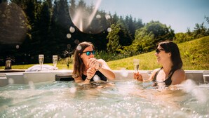 Two people in a hot tub with bubbles, surrounded by greenery and trees. - Laythams Holiday Lets Retreat (Clitheroe)