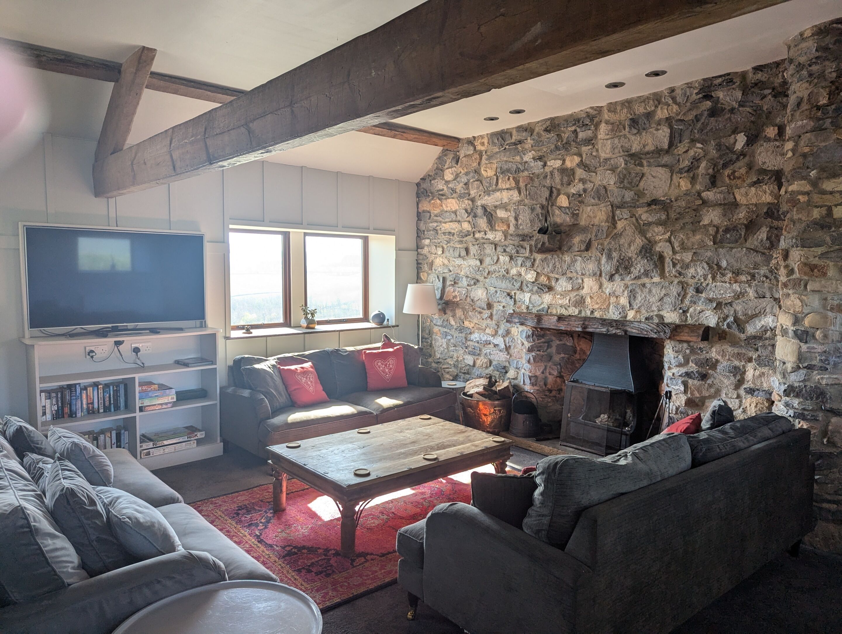 A cozy living room with a stone fireplace, a flat-screen TV, and comfortable seating.