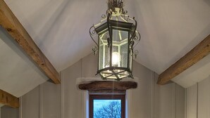 A bedroom with a large bed, two wall sconces, a window with a view, and a ceiling lantern. - Laythams Holiday Lets Retreat (Clitheroe)