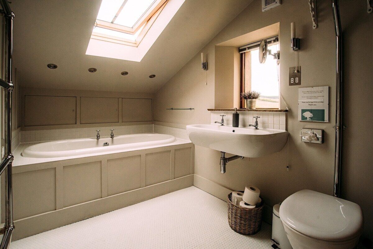 A bathroom with a skylight, a bathtub, a sink, and a toilet.