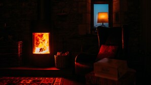 A cozy room with a fireplace, a chair, and a table. - Laythams Holiday Lets Retreat (Clitheroe)