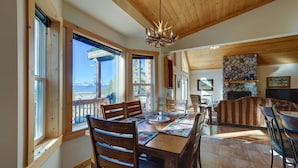 Un coin repas avec une table et des chaises en bois, un lustre et une cheminée en pierre.