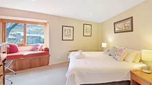 Een slaapkamer met een bed, een vensterbank, een nachtkastje en een lamp.