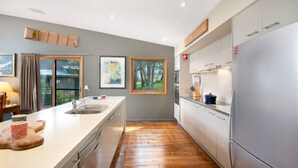 Cozinha moderna com ilha central, eletrodomésticos de aço inoxidável e vista para o exterior.
