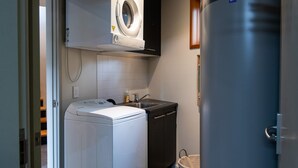Un lavadero pequeño con lavadora y secadora de carga frontal, un lavabo y un cubo de basura.