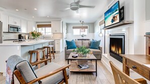 Una cocina moderna con armarios blancos, una isla central y un comedor con muebles de madera.