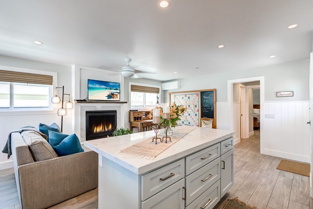 A modern kitchen with a large island, a fireplace, and a dining area with a view of the beach.