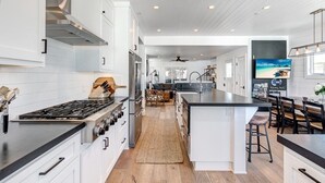 Une cuisine moderne avec des meubles blancs, un îlot central et un coin repas équipé de tabourets de bar.